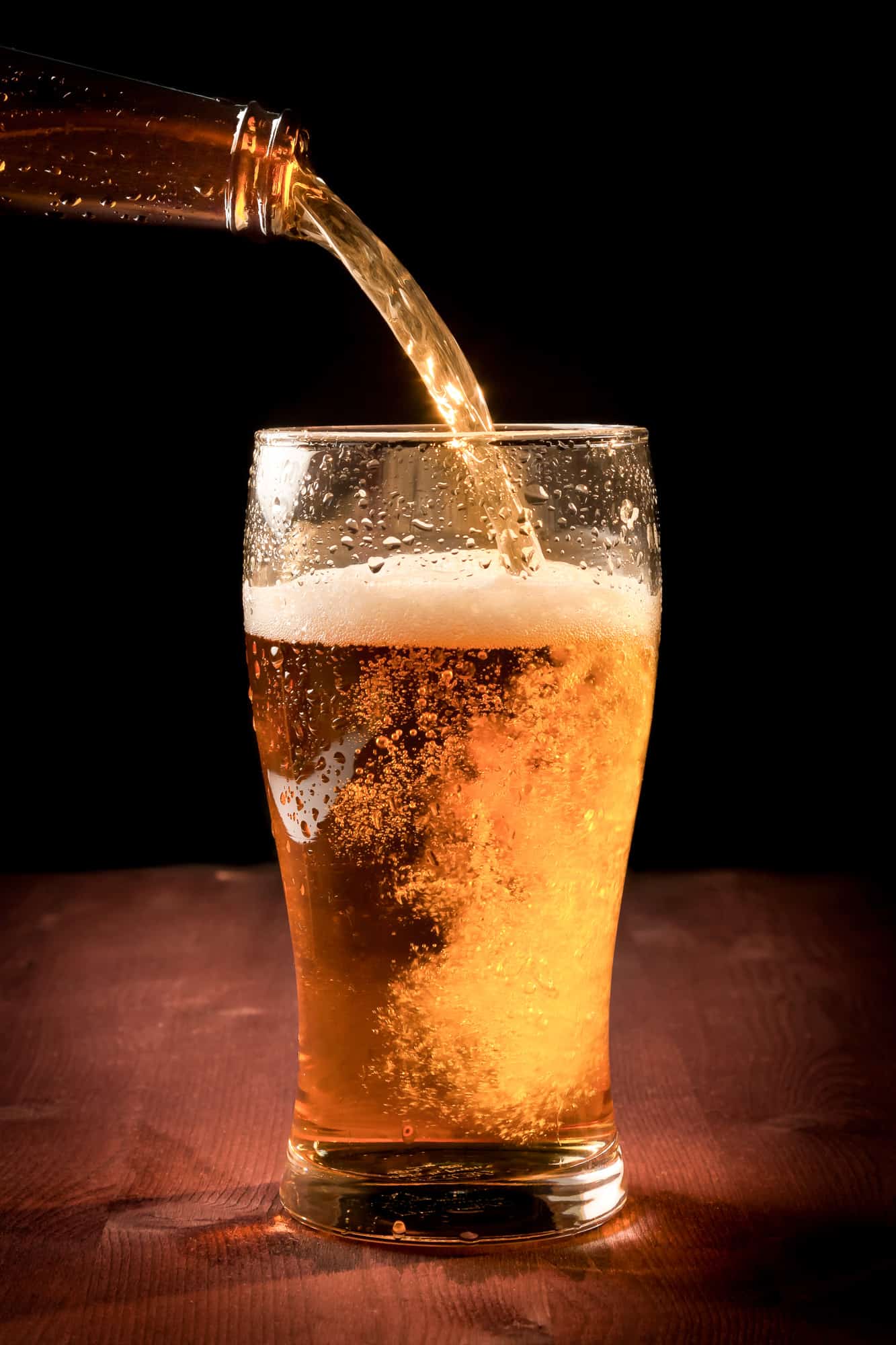 close up of a glass of beer being poured by a bottle, you can find beers from sours to stouts at the breweries in peoria, il