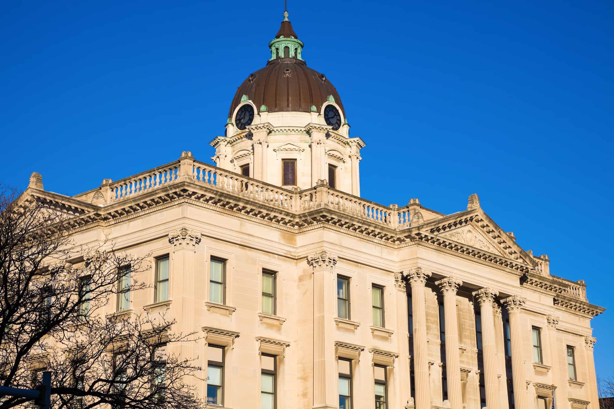 the top half of the local courthouse in bloomington with a dome on top with clocks showing on the 2 sides you can see