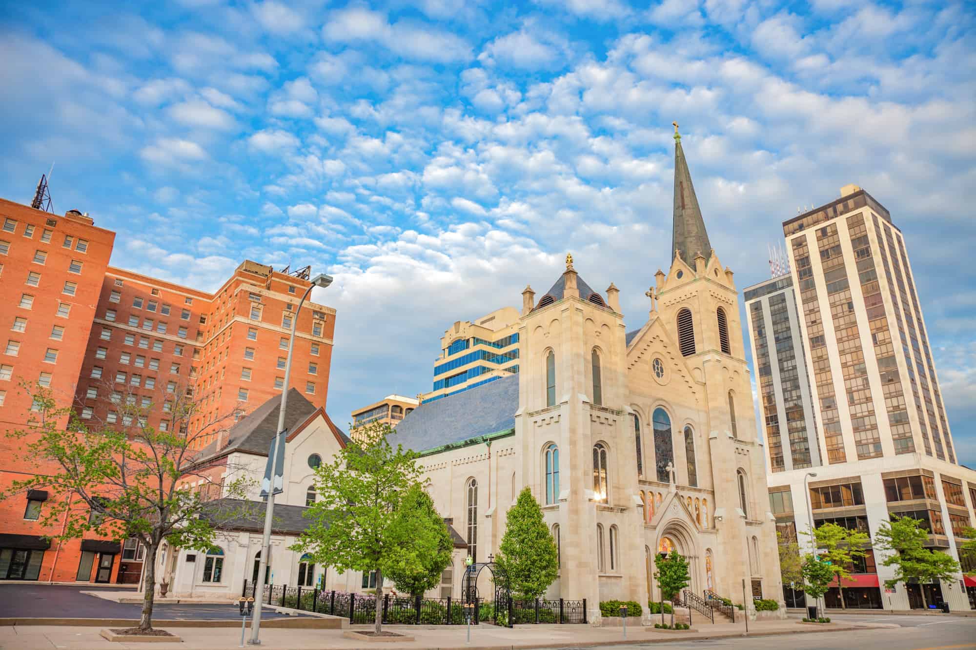 a beautiful church with a steeple stands next to a red brick highrise in downtown peoria, il