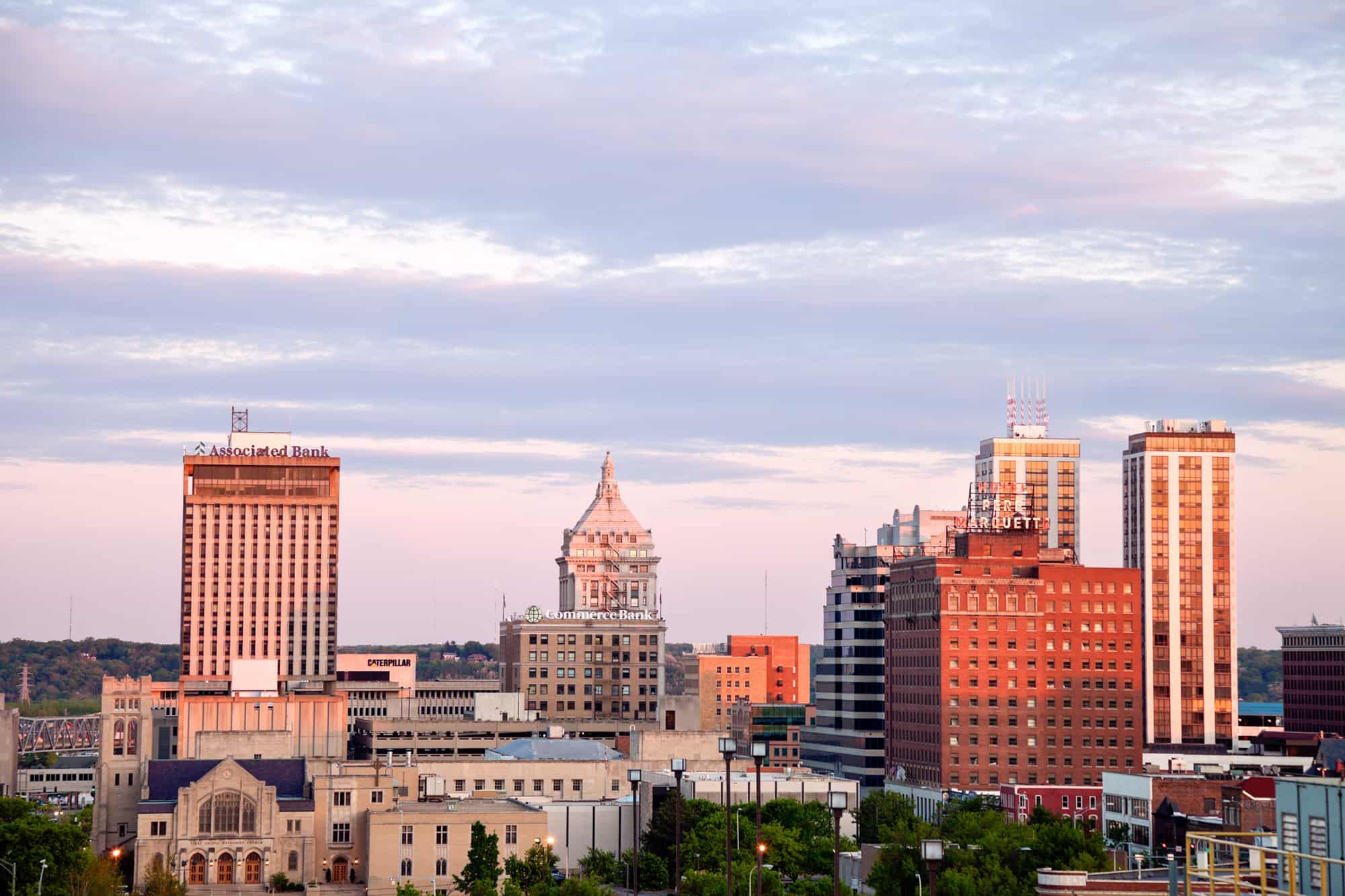 the skyline of Peoria at sunset with golden light shining on the tall buildings of downtown, make sure to check out sunset while visiting the breweries in peoria, il