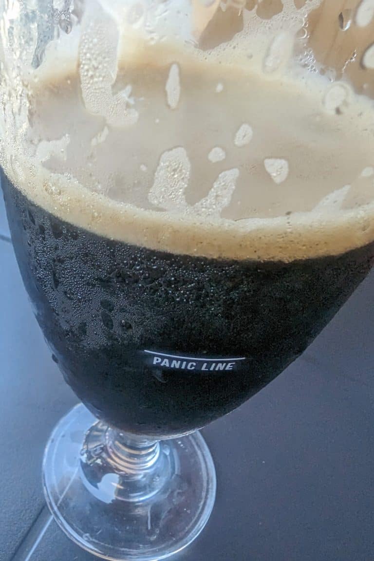 a close up of a pint of beer that has a line that says "panic line" implying that below this line and it is time to panic because you are almost out of beer