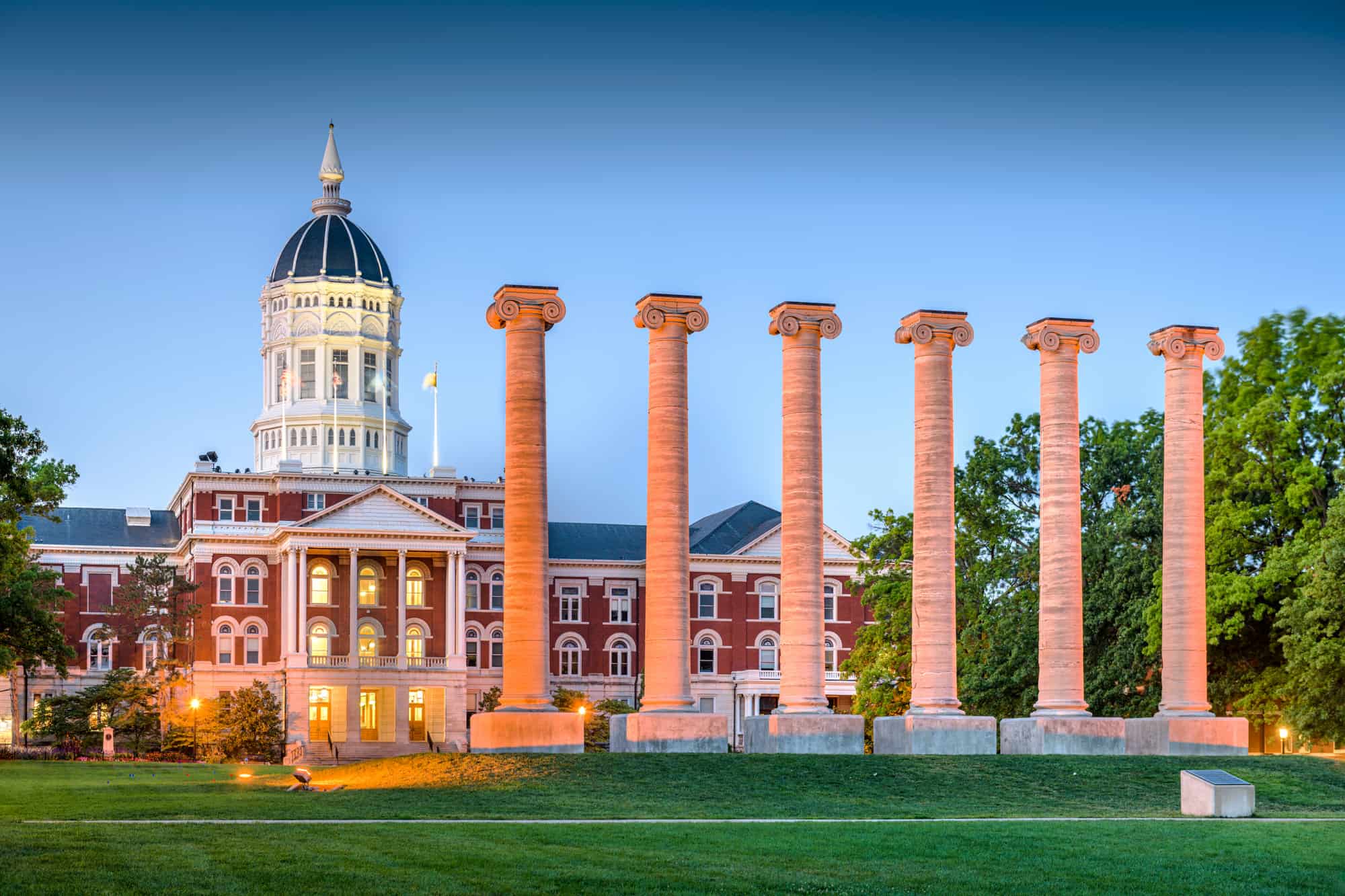 some historic columns stand in a row in columbia missouri in front of a tall building with a rotunda